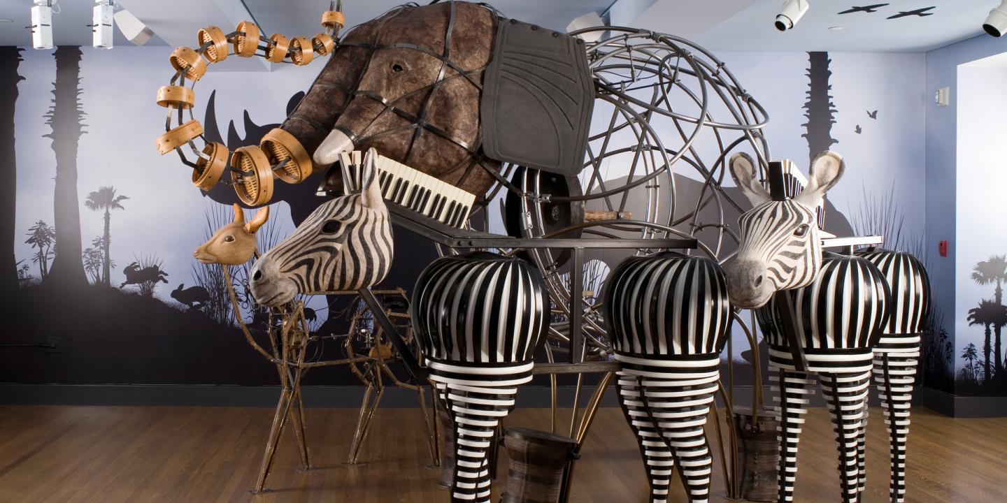 Sculptures of an elephant, two zebra, and a deer made of everyday materials including a keyboard for a zebras mane and floor matts for the elephants ears. 