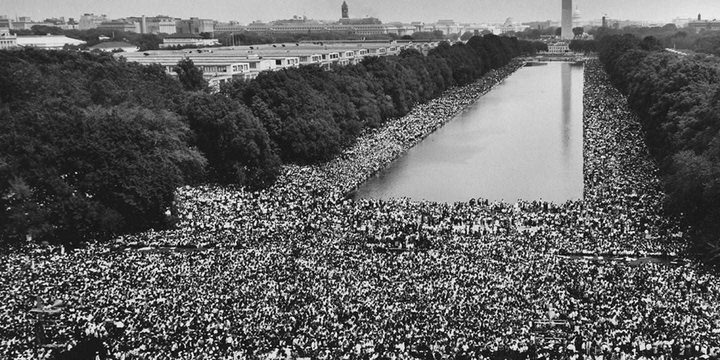 A wide-angle view of marchers along the Mall, showing the Reflecting Pool and the Washington Monument