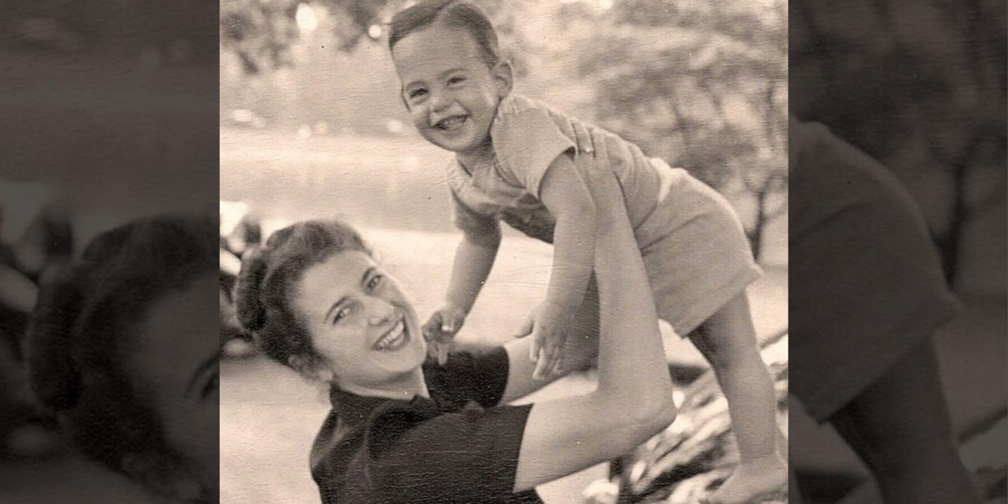 A woman holds a smiling baby in the air as they both look at the camera