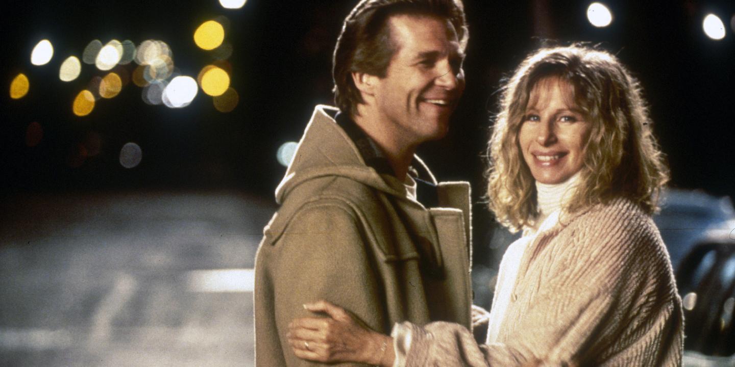 Still from the movie showing Jeff Bridges and Barbara Streisand holding each other and looking toward the camera on a street at night