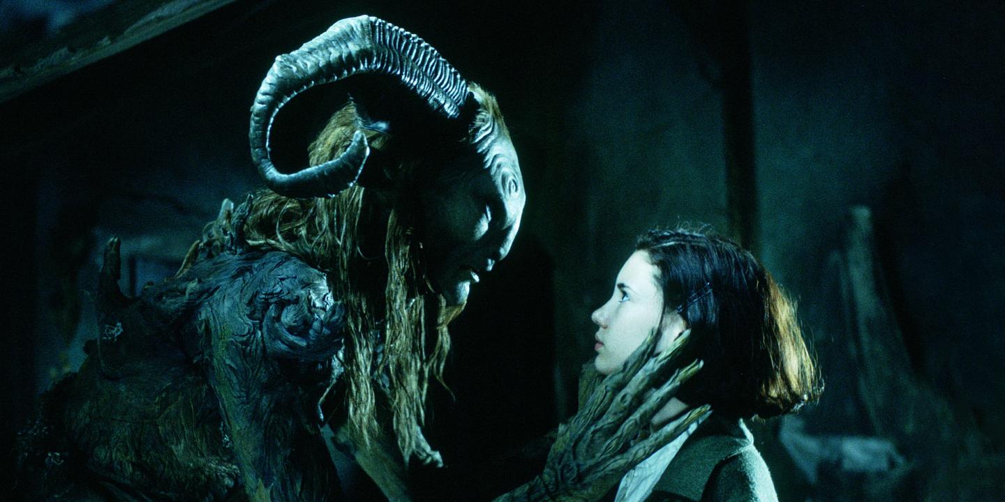 Still from the movie Pans Labyrinth showing the main character, Ofelia, standing face-to-face with a large, horned faun creature.