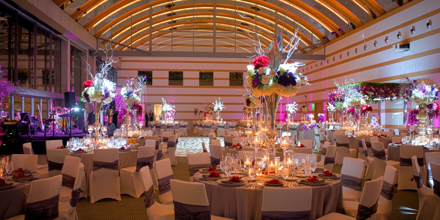 A big event room decorated with tables and flowers.
