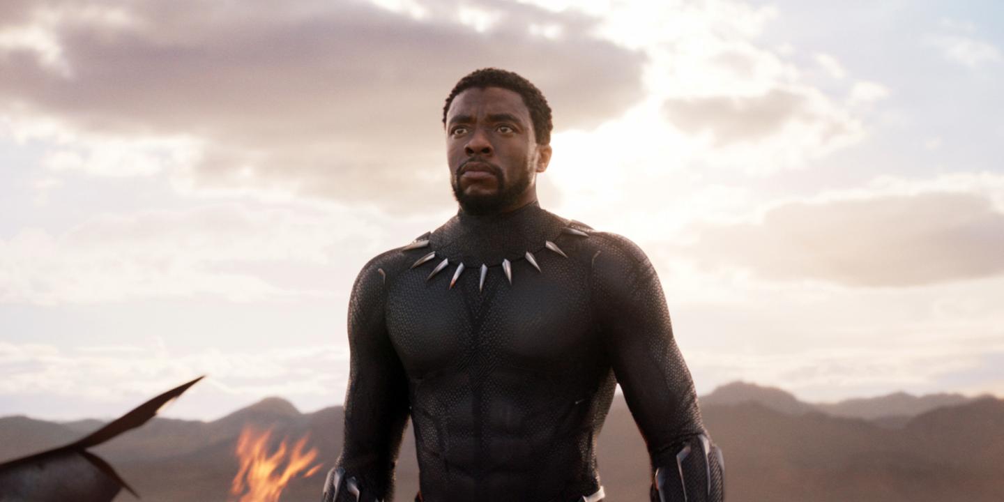 Still from the film showing Black Panther walking towards the camera with a burning ship behind him.