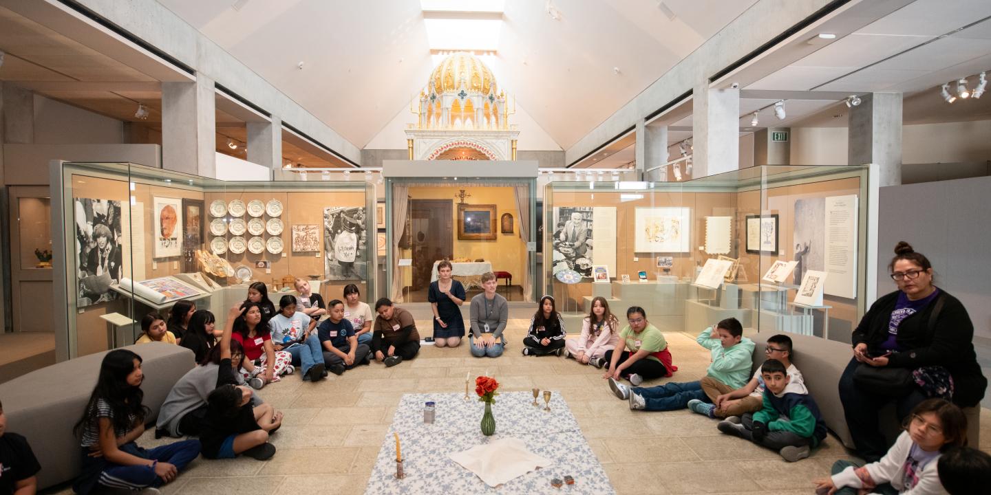 A class gathers around objects in the Visions and Values exhibition.