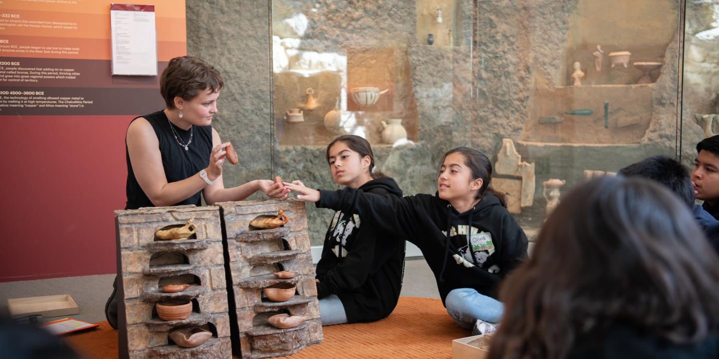A student touches ancient artifacts.