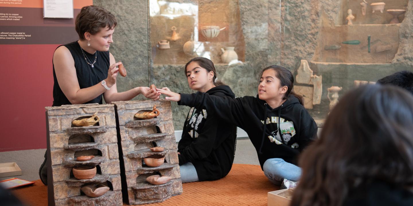 An educator displays ancient pottery for student to touch and talk about.