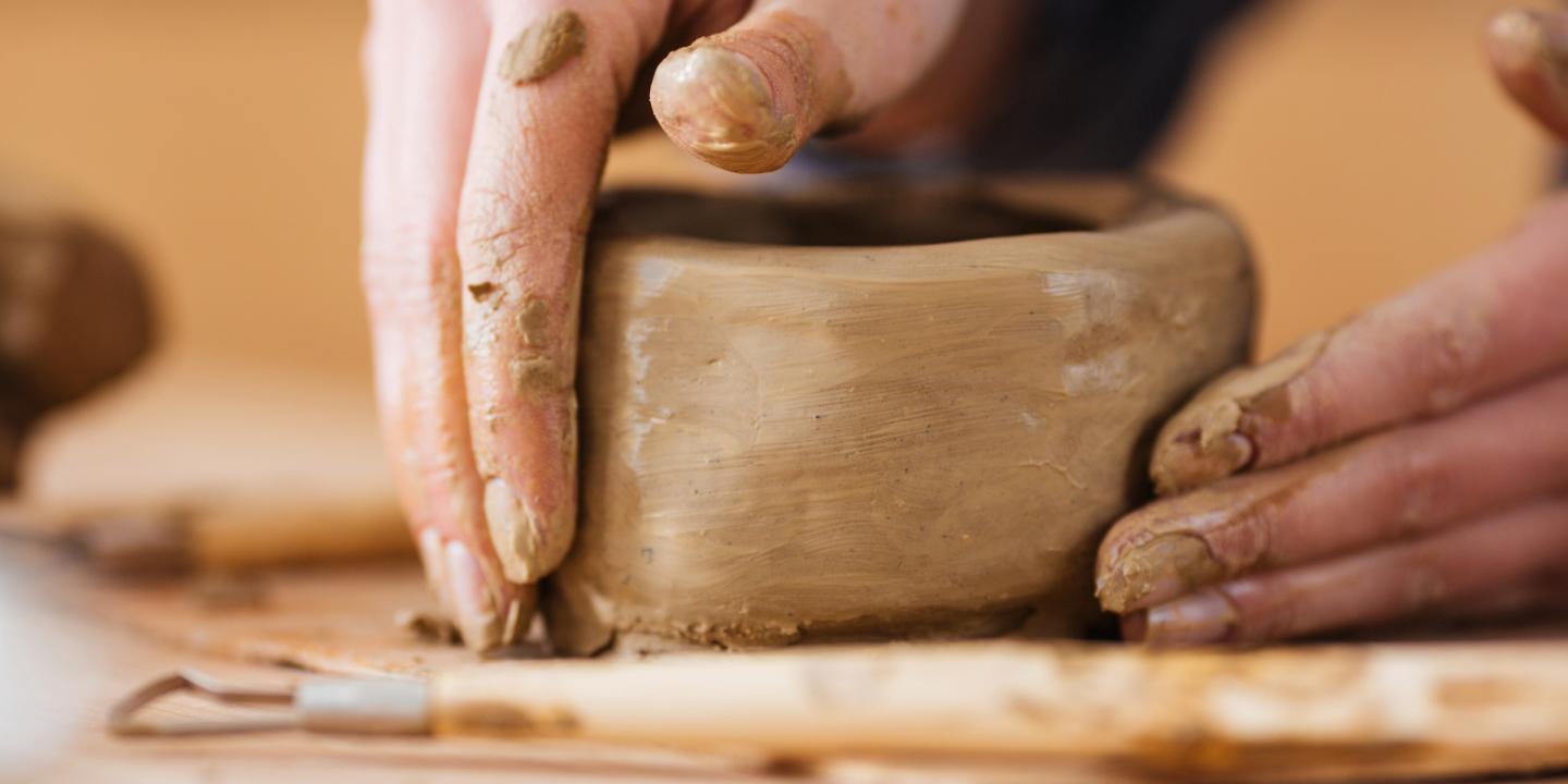 Hands craft a clay bowl.