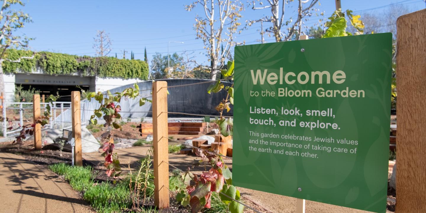 A green sign with white text welcomes visitors to the Bloom Garden.