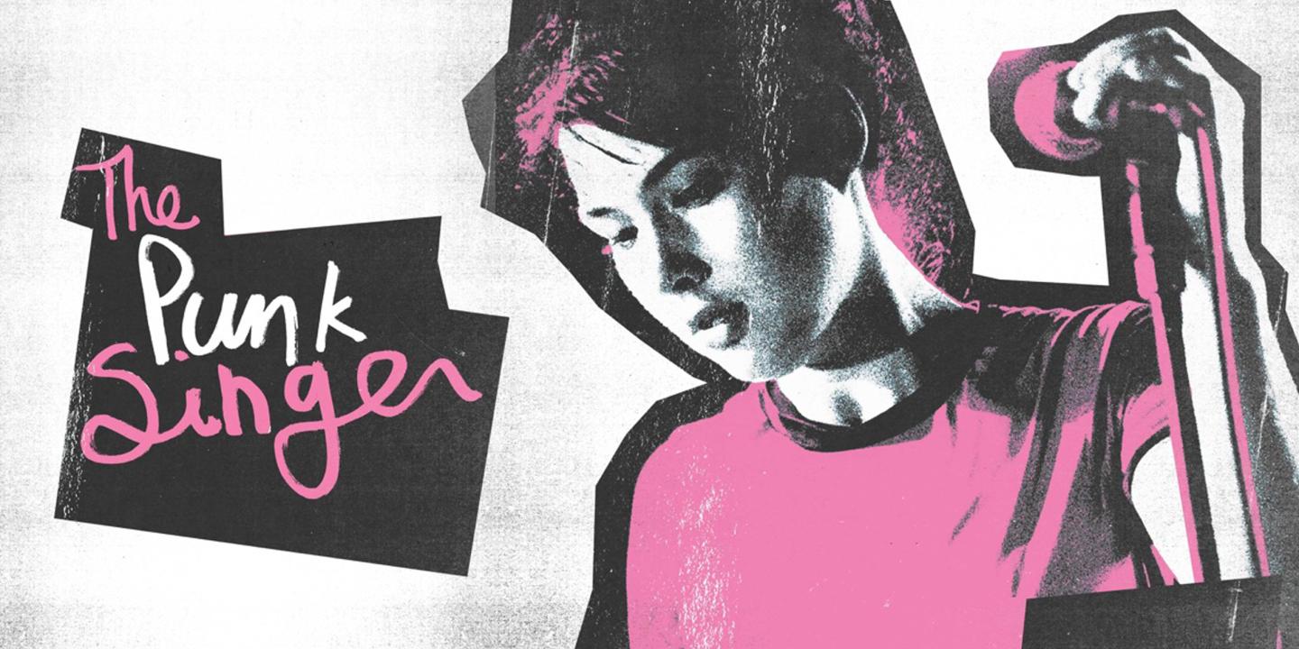 A woman standing in front of a microphone holding it next to the words The Punk Singer in script.