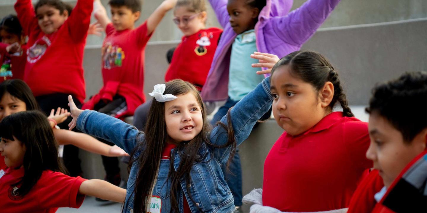 Children with their arms outstretched learning in the ampitheatre