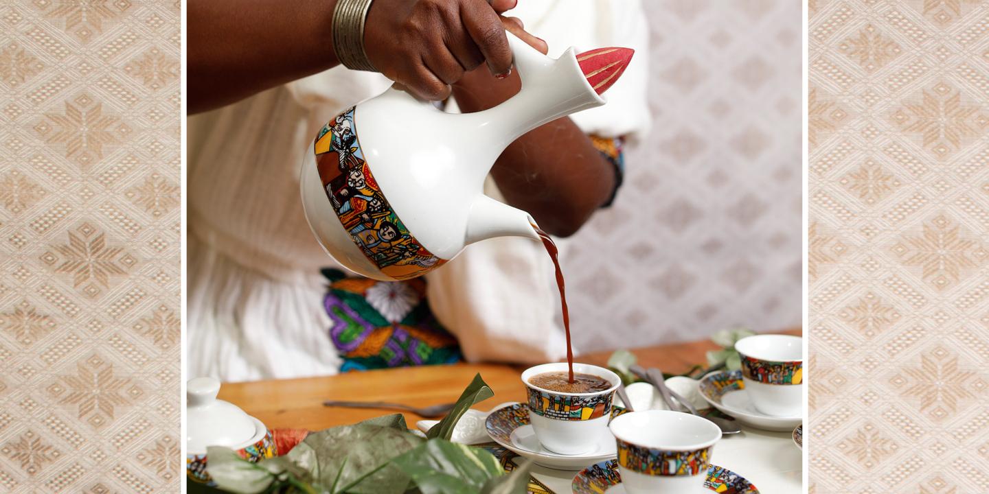 A close up of a person pouring coffee ceremonially in colorfully designed cups.
