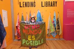 young girl holding up a protest banner that says 'otro mundo es posible'