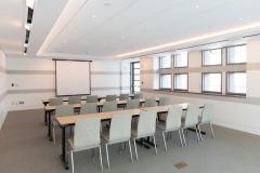 Bergreen Boardroom showing long desks and chairs facing a video projection screen