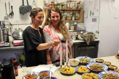 2 women lighting candles on a table that also has many dishes of food