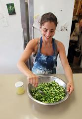 a woman mixing pasta in a metal bowl