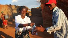 a woman handing a bag of water to a man