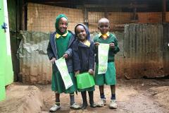 2 young girls and a boy in student uniforms holding up papers that say Peepoo