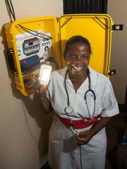 a woman with a stethoscope around her neck holds up a light in front of an open plastic yellow case attached to the wall