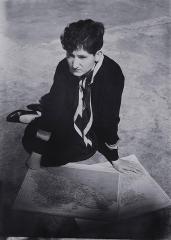 photo of woman sitting on the floor with 2 maps in front of her