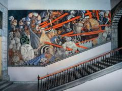 mural on a wall next to a flight of stairs. The mural depicts people in armor attacking people who are not in armor