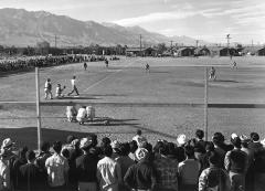 people playing baseball while a group of other people watch the game