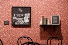 artwork  and books on wall covered in patterned wallpaper with chairs arranged in front