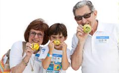 a woman, child, and a man holding up lemons that have faces drawn on them