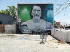 mural on the side of a building showing a bust of a man with a mustache and an old car
