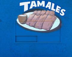mural on a blue wall depicting a plate of tamales with the word 'Tamales' painted above them