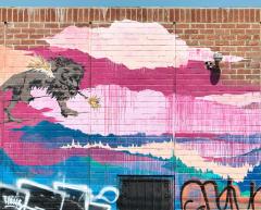 colorful mural of a lion walking on a wire holding a stick in its mouth