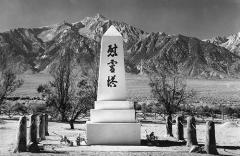 an obelisk painted white with 3 black Japanese characters; in the distance is a mountain