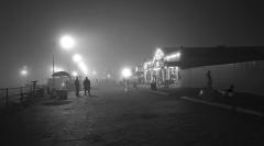 people on a large foggy pier with buildings in the background