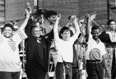 people on stage including Paul Simon holding hands held up high