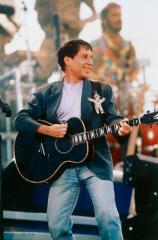 Paul Simon at a concert strumming a guitar