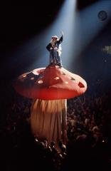 an old man with a long white beard standing on top of a larage paper mushroom