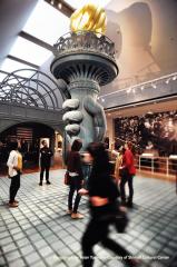 people viewing large-scale model of Statue of Liberty hand and torch