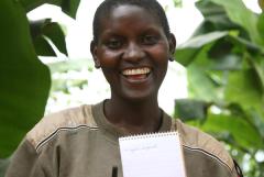 a woman smiling holding up a spiral notebook