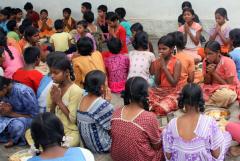 a group of children seated on the ground with their hands held together in prayer