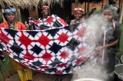 women holding up a large tie-dyed cloth