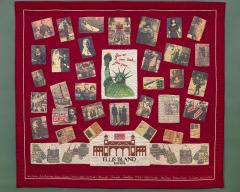 A red quilt with rectangular images sewn on. There is a picture of the Statue of Liberty and building that say Ellis Island. The other images are of immigrant families.