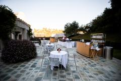 Outdoor reception set up with round tables and bar in a lush, green space