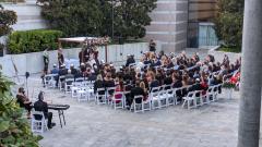 View of an outdoor wedding ceremony showing guests seated in white chairs and the bride and groom standing under a chuppah