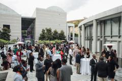 An outdoor reception filled with people standing and mingling together amidst with high top tables and outdoor heaters