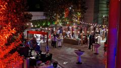 Nighttime, outdoor reception of people standing under strings of lights in a courtyard