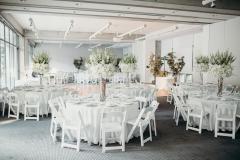 View of a large room filled with tables and large floral displays for a formal reception