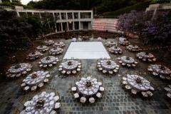 The courtyard set up for a wedding reception. Tables with white linens are set up around a dance floor