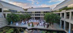 The courtyard set up for a wedding reception. Tables with white linens are set up around a dance floor and a blue sky is seen overhead.