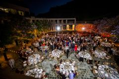 A large group dancing in an outdoor courtyard with a lily pond decorated with lights, tables, and a dance floor.