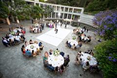 A couple dancing in an outdoor courtyard with a lily pond decorated with lights, tables, and a dance floor.