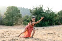 woman in an orange dress and long dark hair dancing in the sand